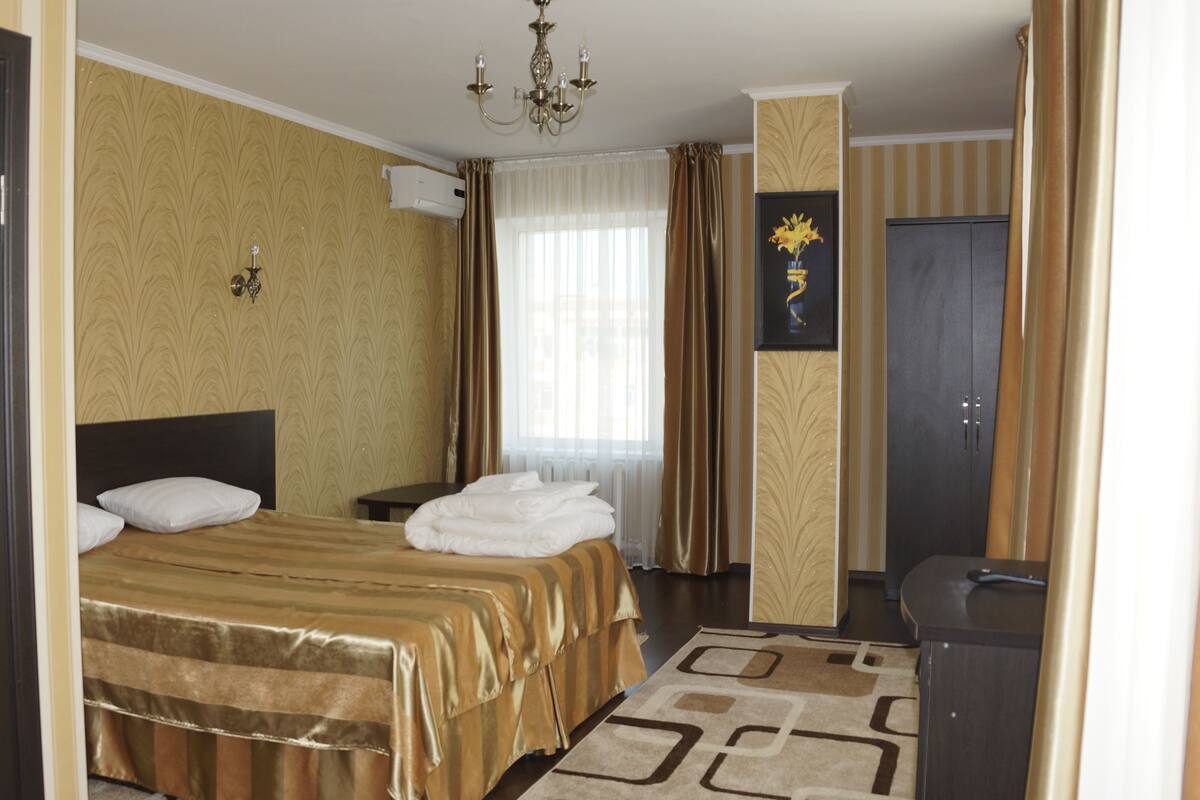 A hotel room with a bed, a desk, a chair, a wardrobe, and a bathroom.