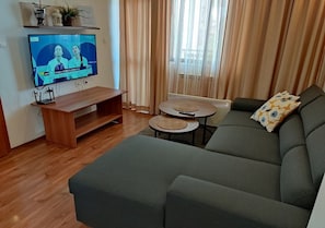 Relax in this stylish living room with a large sofa, flat-screen TV, and wooden coffee table.