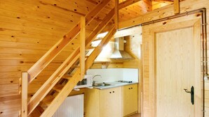 Un interior de madera con una zona de cocina, una escalera y una puerta.