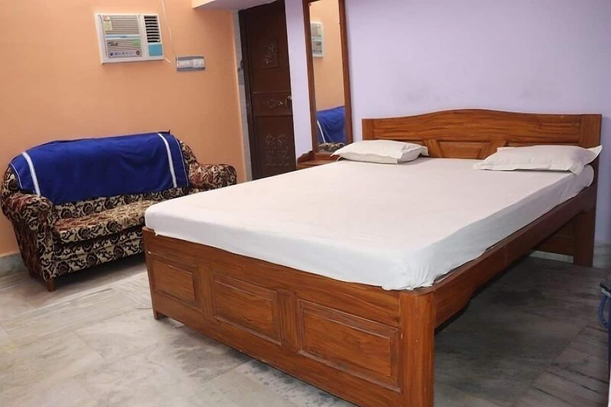 A room with a wooden bed, a patterned sofa, and a tiled floor.