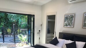 Ein Schlafzimmer mit einem großen Bett, einer Tür, die auf einen Balkon führt, und einer Wand-Klimaanlage.