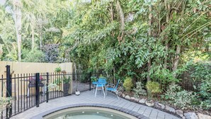 Ein Garten mit Whirlpool, Holzterrasse und schwarzem Metallzaun.