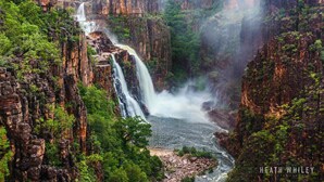 Ein Wasserfall stürzt über eine steile Felswand herab, umgeben von dichtem Grün.