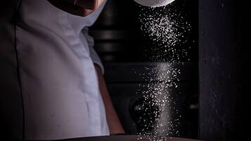 A person in a white shirt pouring a granular substance into a bowl.