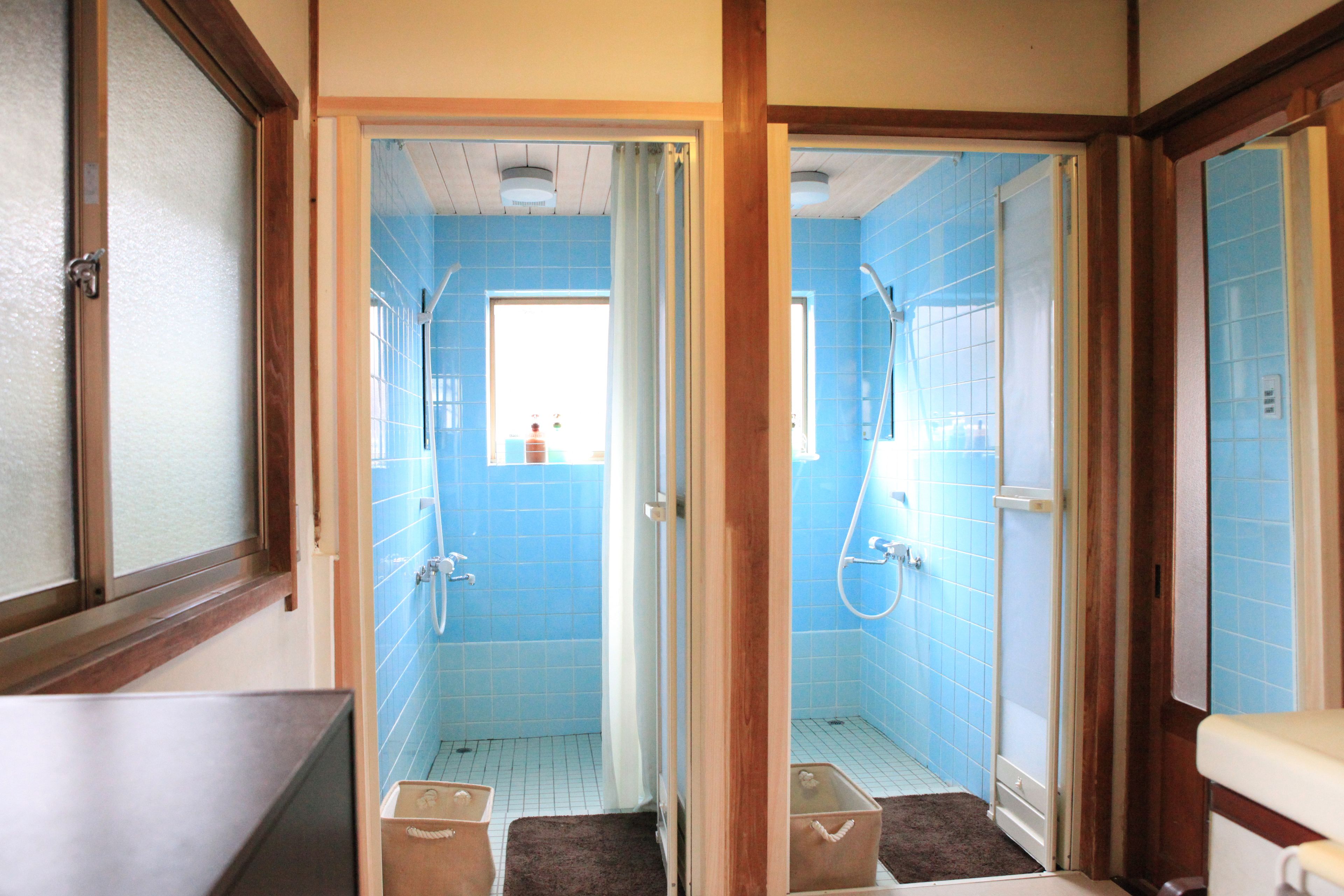 A bathroom with blue tiles, a shower, and a toilet.