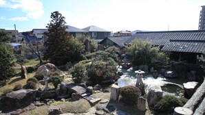 Un jardín japonés tradicional con faroles de piedra, un estanque y una valla de madera.
