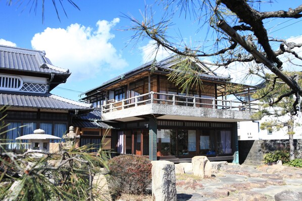 A traditional Japanese building with a wooden structure, a balcony, and a stone pathway.