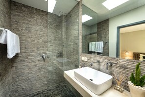 Une salle de bain moderne avec une douche à parois de verre, un grand miroir et un lavabo blanc.