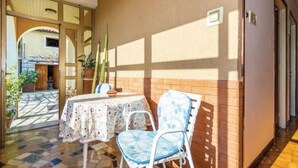 An outdoor patio with a table and chairs, a tiled floor, and potted plants. - Apartment Kumicic (Opatija)
