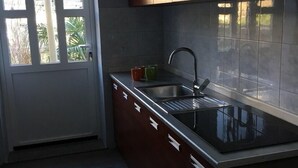 A modern kitchen with dark wooden cabinets, a stainless steel sink, and a window providing natural light. - Apartment Kumicic (Opatija)