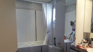 A small bathroom with a toilet, sink, and shower area. - CHAMBRE D'HÔTE CONFORTABLE (Voisins-le-Bretonneux)