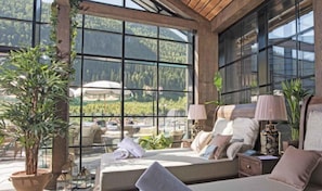 Enjoy a scenic view of the mountains from the large window in this guest room, featuring a comfortable bed and potted plants.