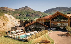 Un moderno lodge con piscina, mobiliario exterior y vistas a la montaña.