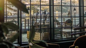 A room with large windows offering a view of a mountainous landscape and a lake. - Fyri Resort Hemsedal (Hemsedal)