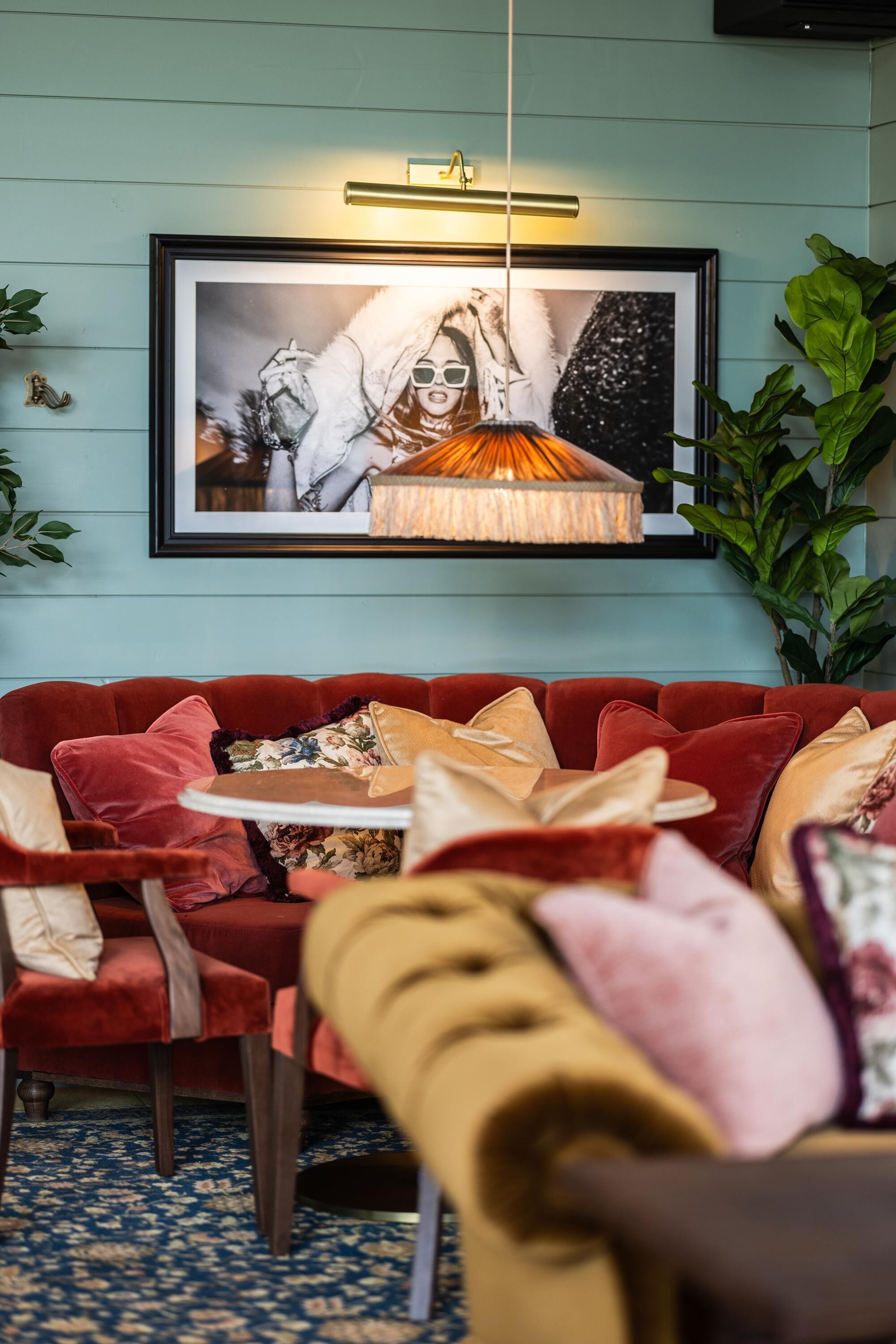 A cozy seating area with a red sofa, a small round table, and a framed artwork above.