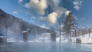 A clear blue sky with scattered clouds, a snow-covered mountain range, and a pool with steam rising from the water. - Fyri Resort Hemsedal (Hemsedal)