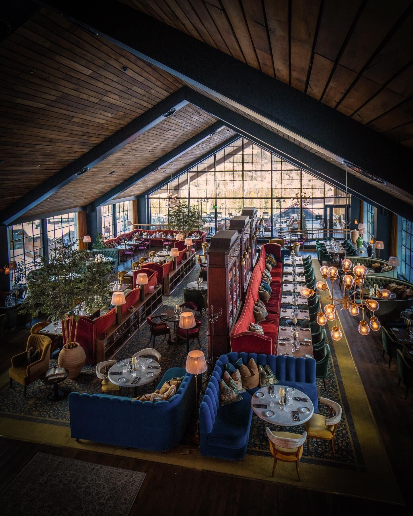 A spacious indoor area with multiple seating arrangements, including sofas and tables, and a high ceiling with wooden beams.
