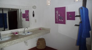 A bathroom with two sinks, a mirror, and wall-mounted artwork. - Warm Sea Sand (Diani Beach)