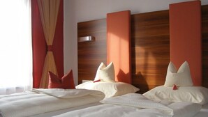 Een hotelkamer met twee bedden, rode gordijnen en een houten hoofdeinde.