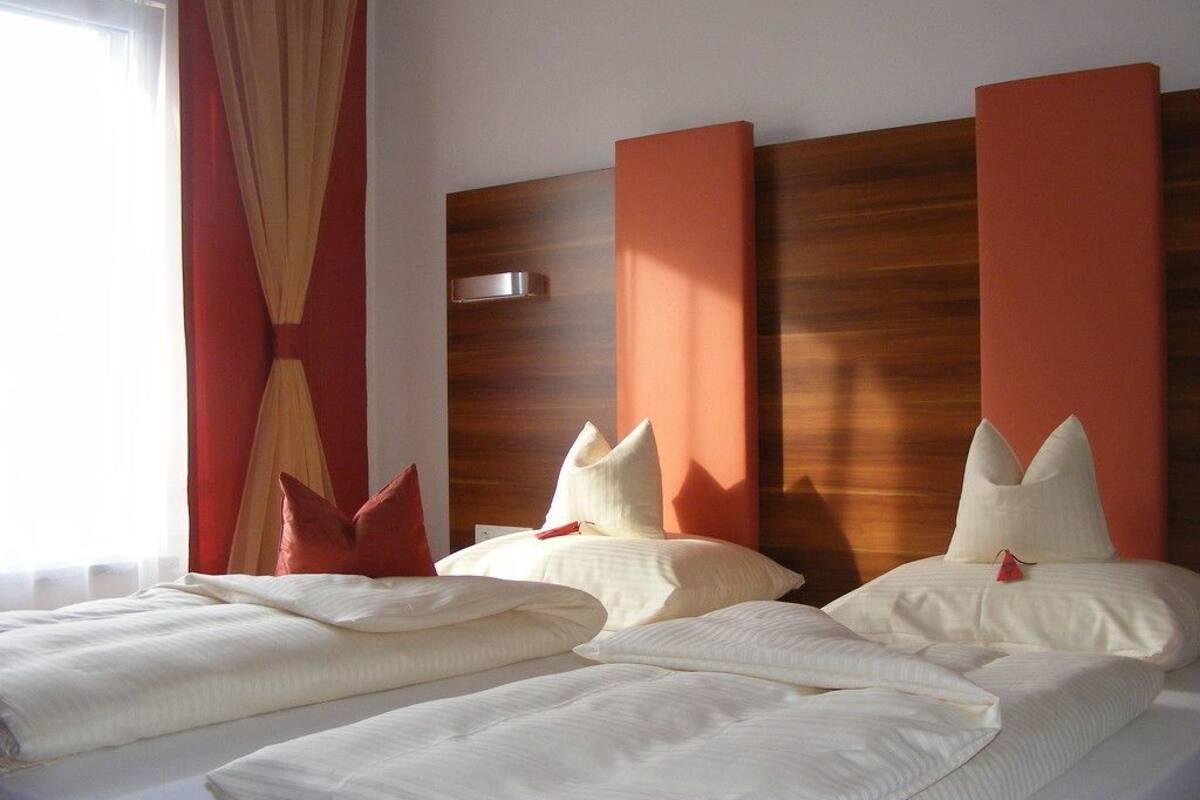 Una habitación de hotel con dos camas, cortinas rojas y un cabecero de madera.