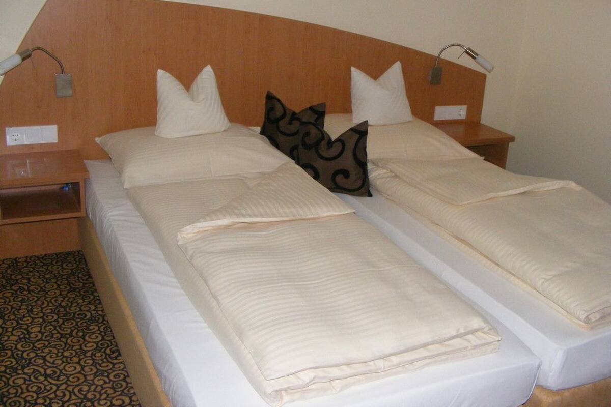 Una cama doble con cabecera de madera, dos mesitas de noche y un suelo estampado.