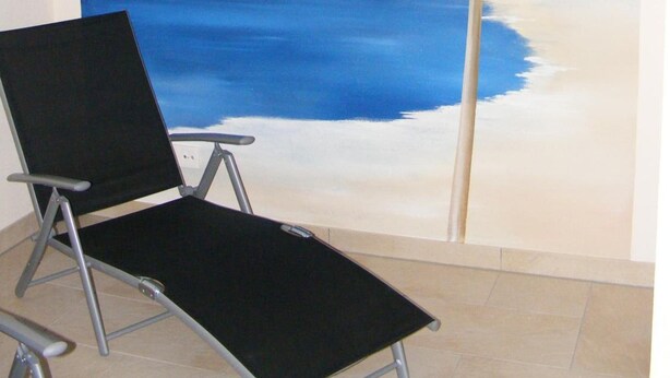 Een kamer met een strandmuur, een zwarte stoel en een betegelde vloer.