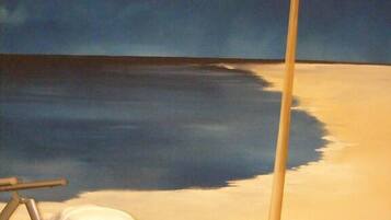 Eine Strandansicht mit Liegestuhl und Sonnenschirm, ruhigem Meer und blauem Himmel.
