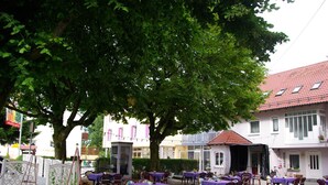 Een terras met tafels en stoelen, omgeven door bomen en gebouwen.