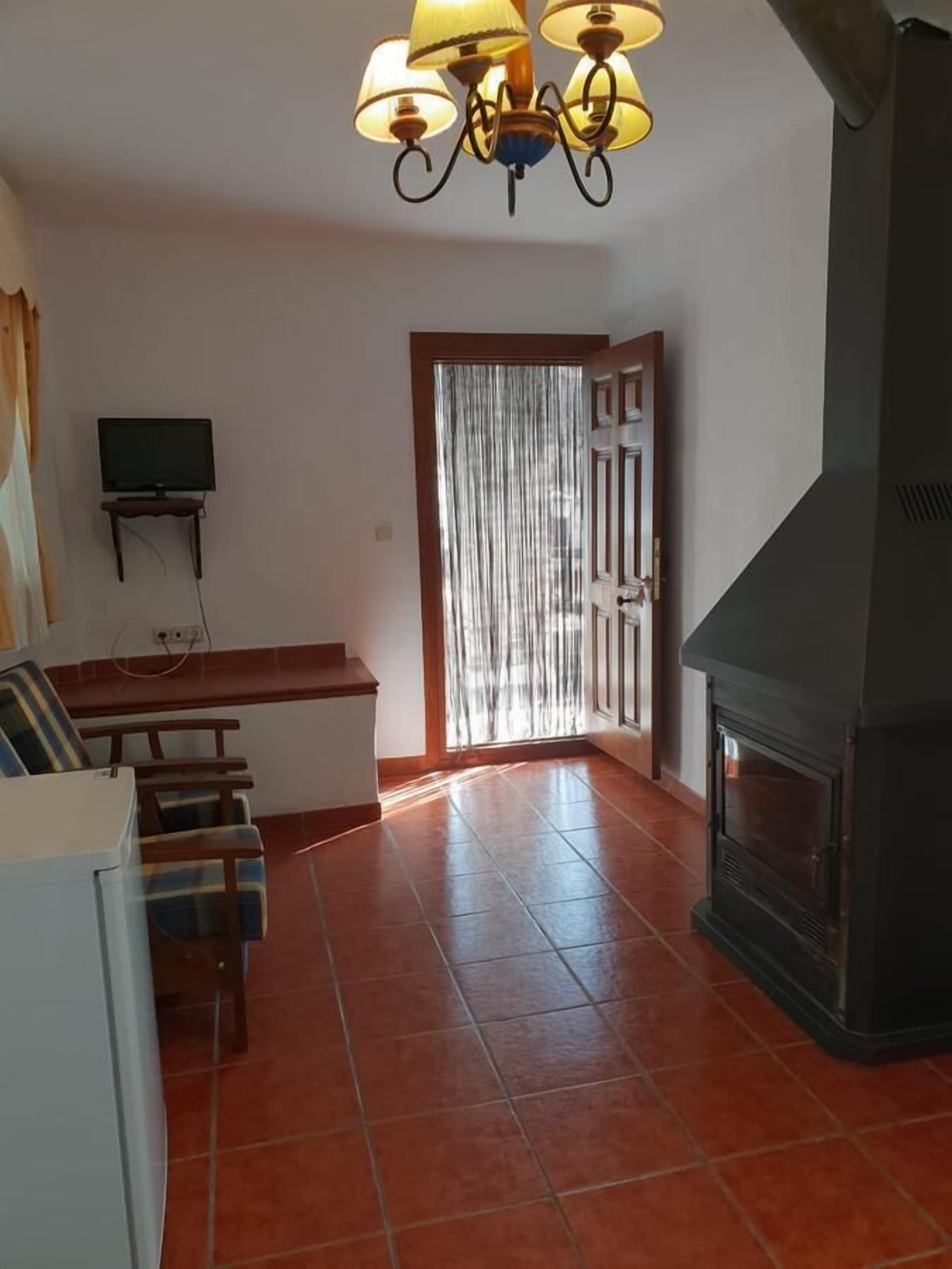 Una sala de estar con chimenea, un televisor sobre un mueble bajo, un sofá y un comedor.