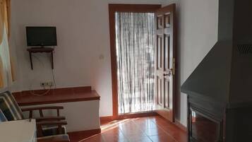 Una sala de estar con chimenea, un televisor sobre un mueble bajo, un sofá y un comedor.