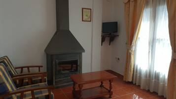 Una sala de estar con chimenea, sofá, mesa y cortinas.
