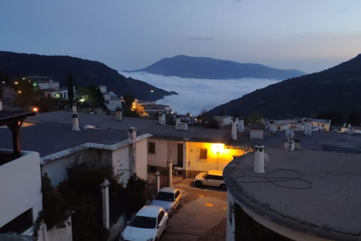A residential area with houses, a parked car, and a mountain in the background.
