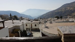 A mountainous village with traditional architecture, including white buildings with flat roofs and a central courtyard.