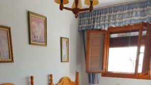 A bedroom with two wooden beds, a window with curtains, and a ceiling fan. - Hostal Rural Ruta de las Nieves (Capileira)