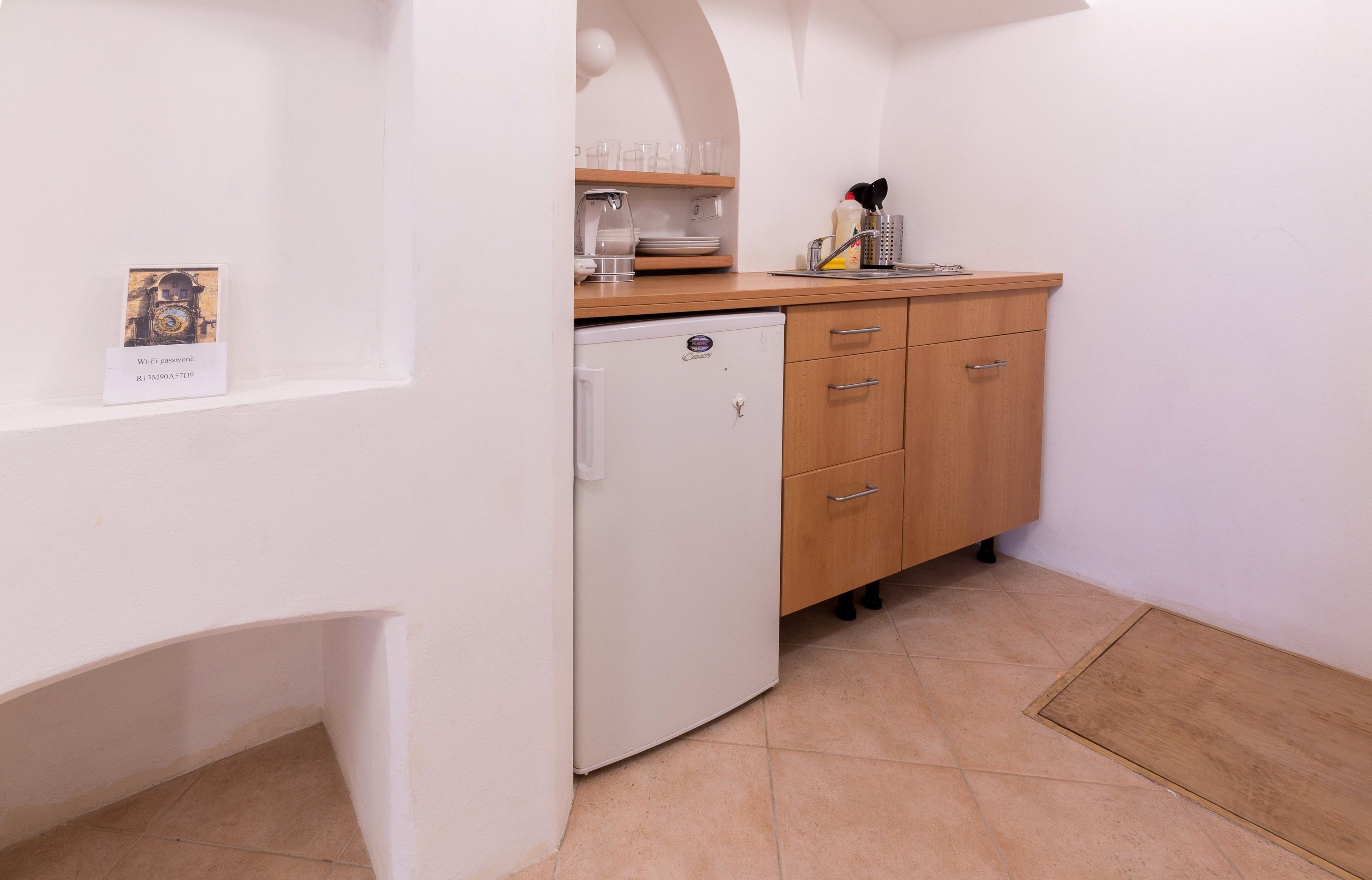 A compact kitchen with a white refrigerator, wooden cabinets, and a small countertop.