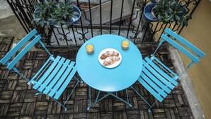 A blue metal table and chairs set on a wooden floor, with a plate of croissants and two glasses of orange juice. - Charles Bridge Economic Hostel (Prague)