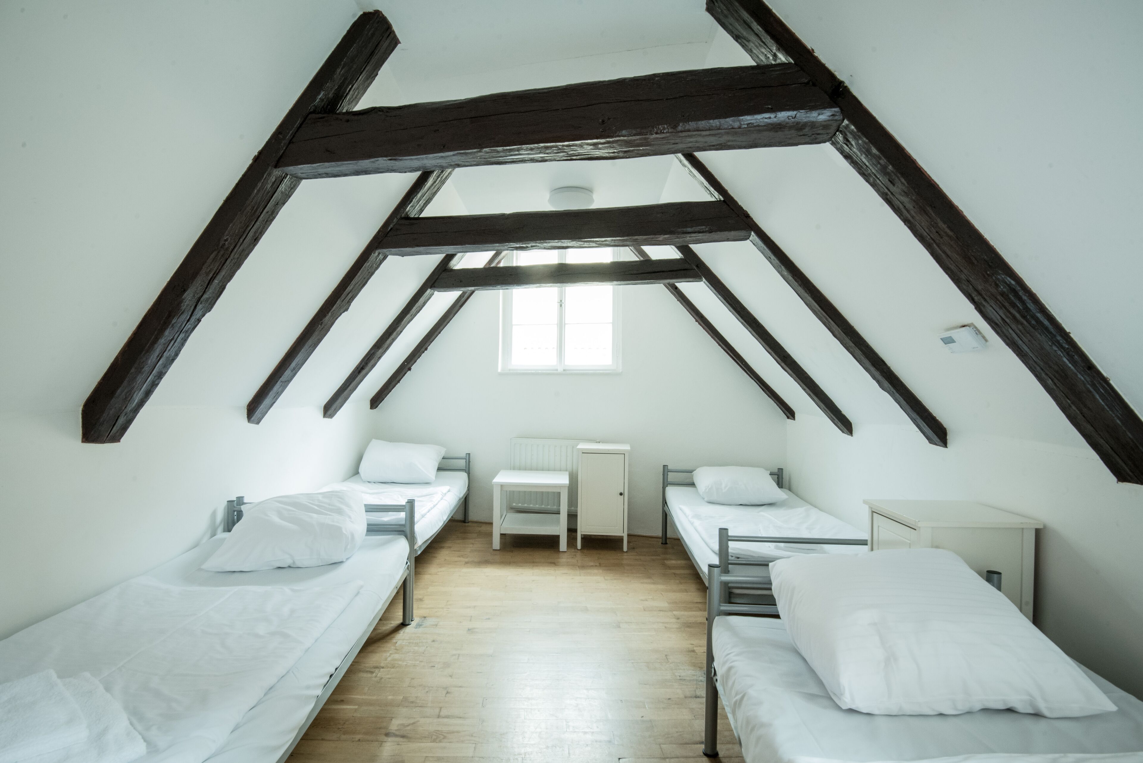 A dormitory room with two single beds, a small table, and a window.
