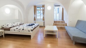 A room with a bed, a sofa, a table, and a staircase leading to another room. - Charles Bridge Economic Hostel (Prague)
