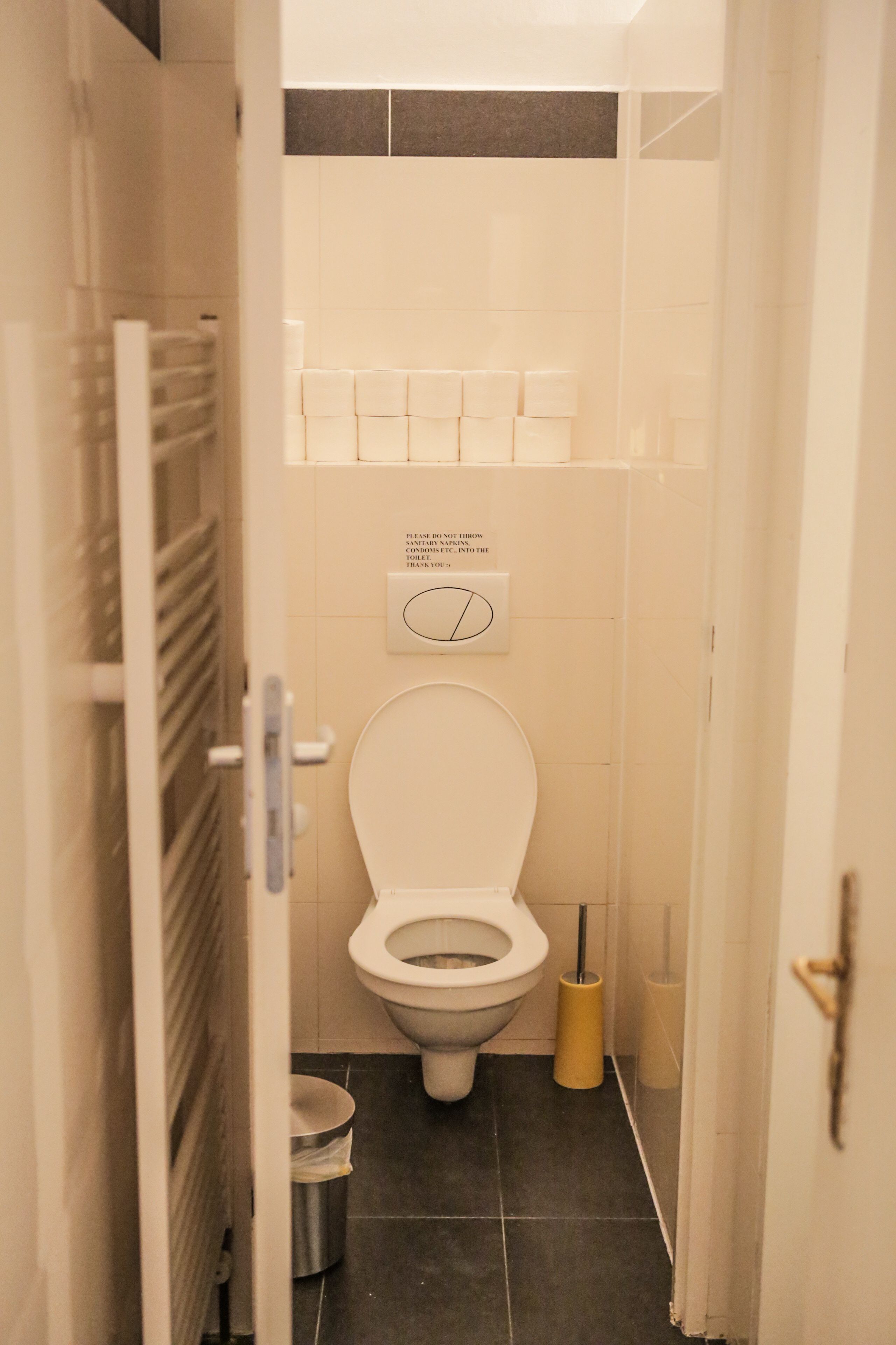 Une petite salle de bain compacte, équipée de toilettes, d’une poubelle et d’un sèche-mains.