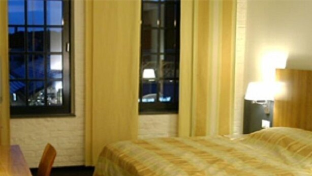 A hotel room with a bed, a desk, and a chair. - Hotel Lederfabrik (Muelheim an der Ruhr)