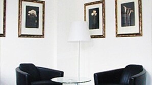 A room with two black leather chairs, a white floor lamp, and three framed pictures on the wall. - Hotel Lederfabrik (Muelheim an der Ruhr)