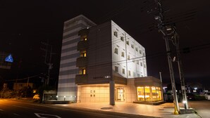 Un hotel moderno con una entrada destacada, varios pisos y una fachada bien iluminada.