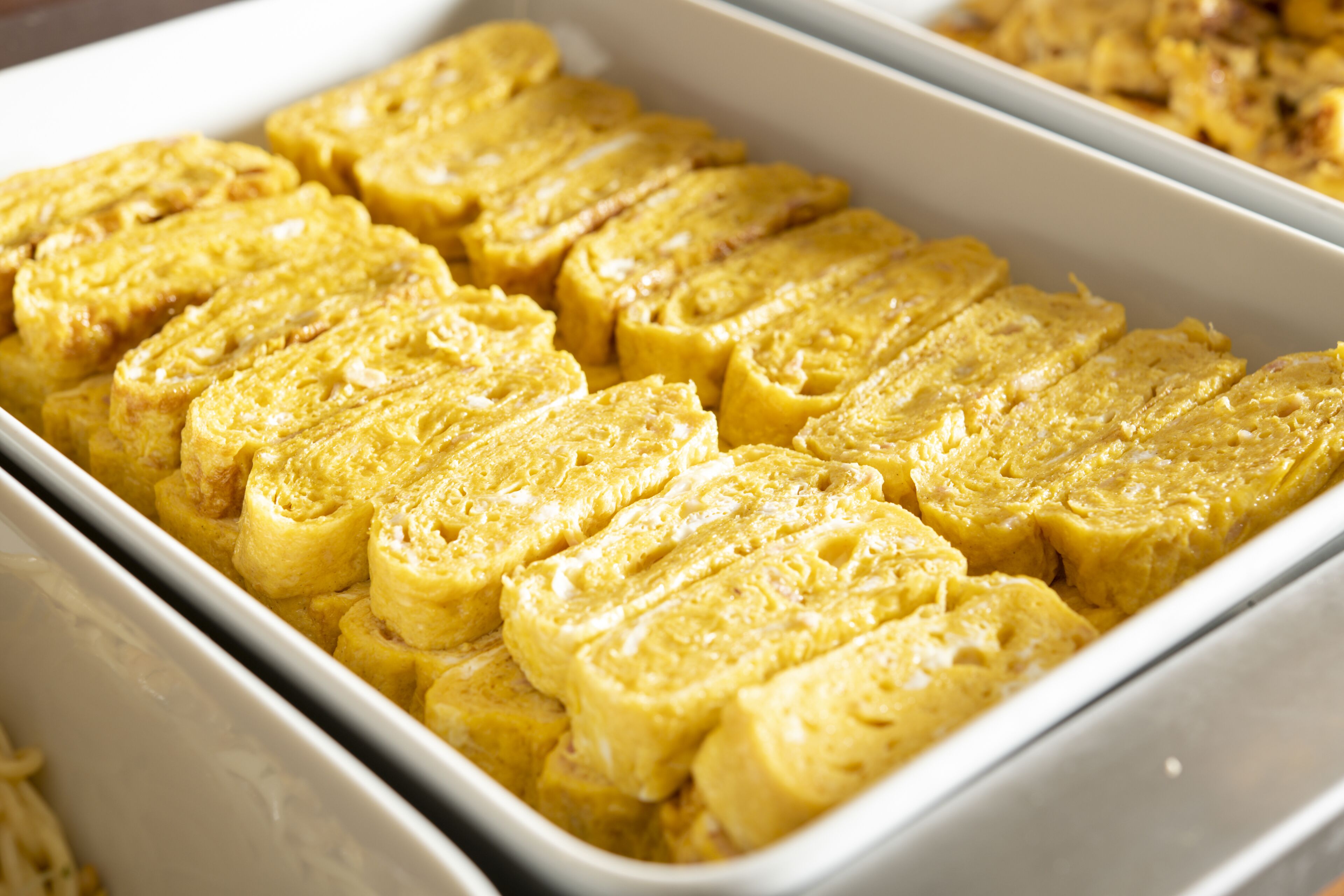 A white rectangular serving dish containing several square pieces of a yellow food item, possibly a type of bread or pastry.