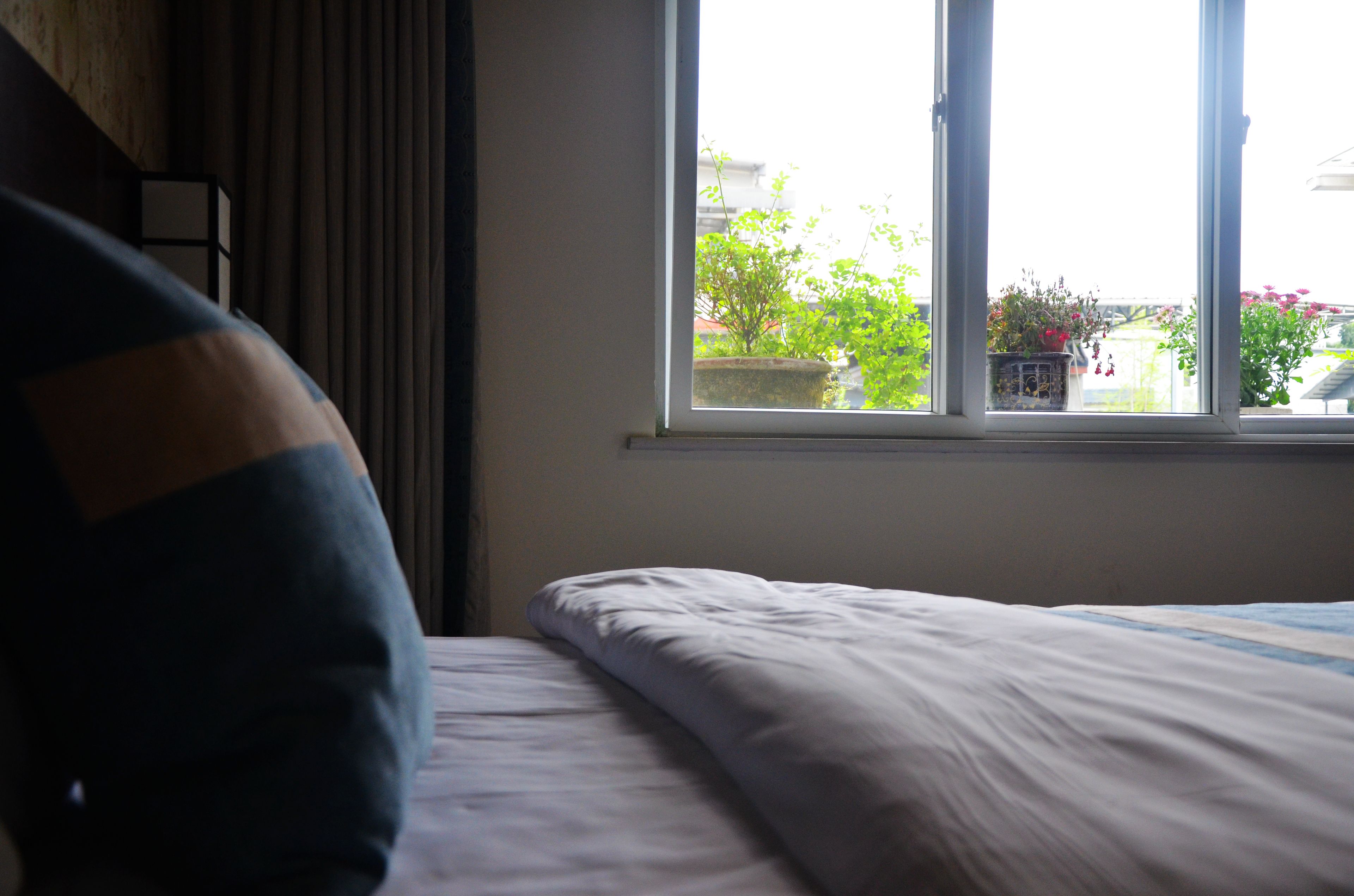 A bedroom with a bed, a window, and a view of greenery outside.