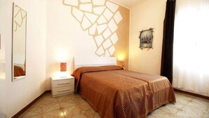 Une chambre d’hôtel avec un lit, une table de chevet, une lampe et un élément décoratif mural.