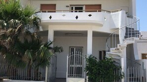 Un immeuble à deux étages doté d’un balcon, d’une entrée sécurisée par un portail et d’un escalier menant à l’étage supérieur.