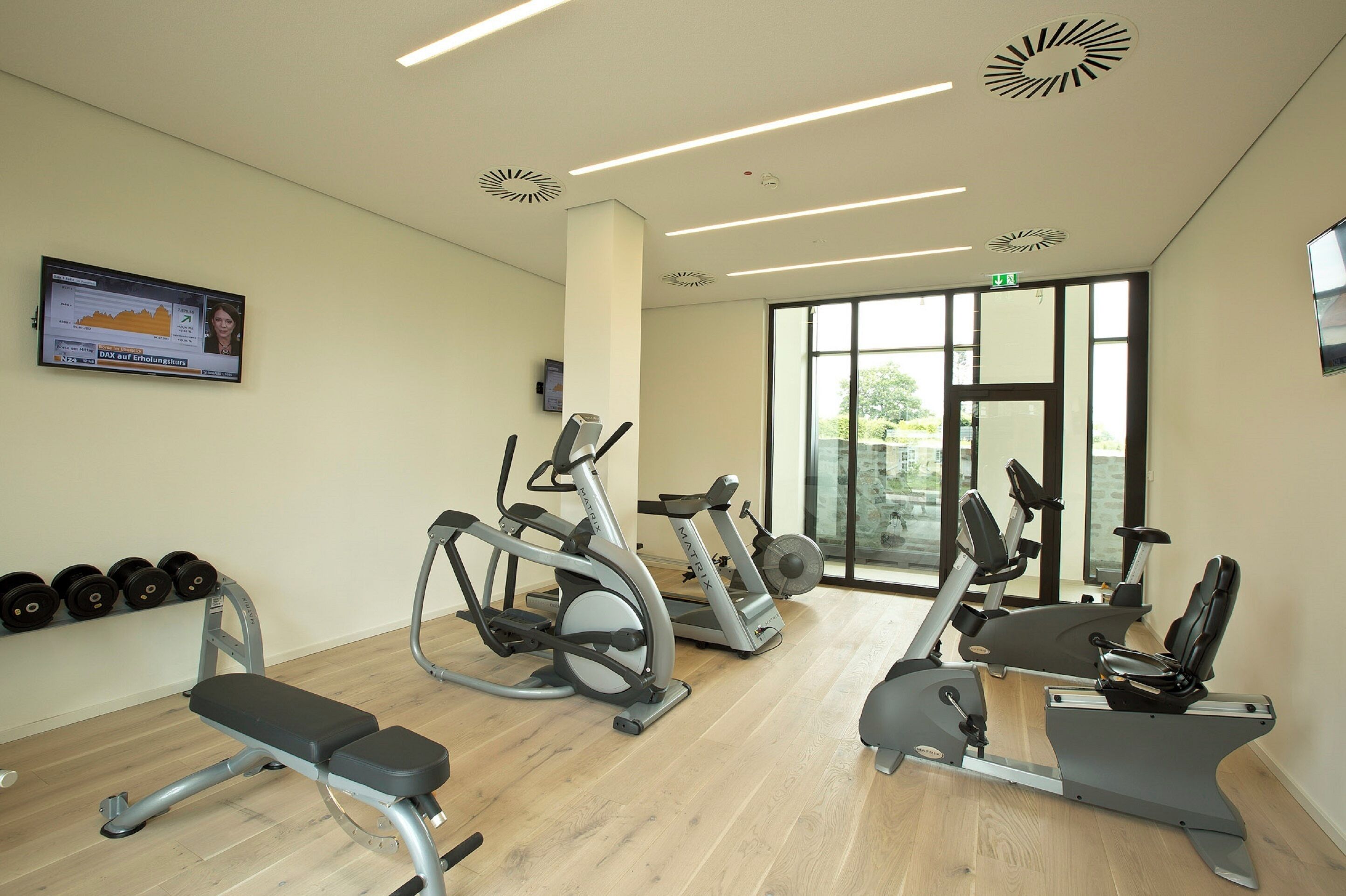 A gym with cardio machines, dumbbells, and a bench.