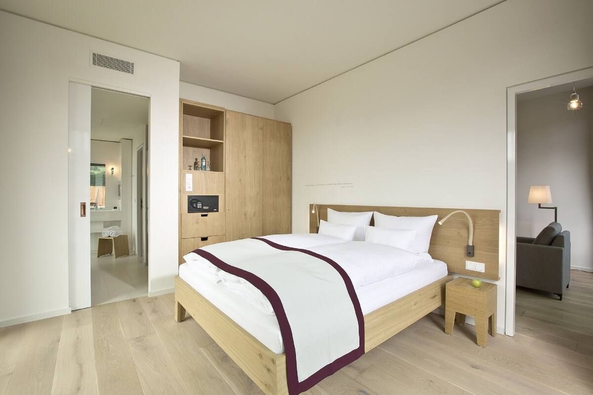A modern bedroom with a wooden bed, a nightstand, a small table, and a wardrobe.