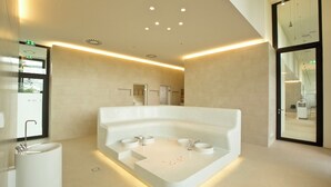 Een moderne badkamer met een vrijstaand ligbad, twee wastafels en een spiegel.