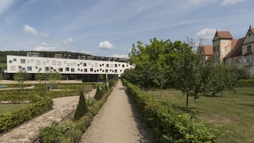 Ein Weg führt zu einem modernen Gebäude, im Hintergrund ist ein traditionelles Gebäude zu sehen.